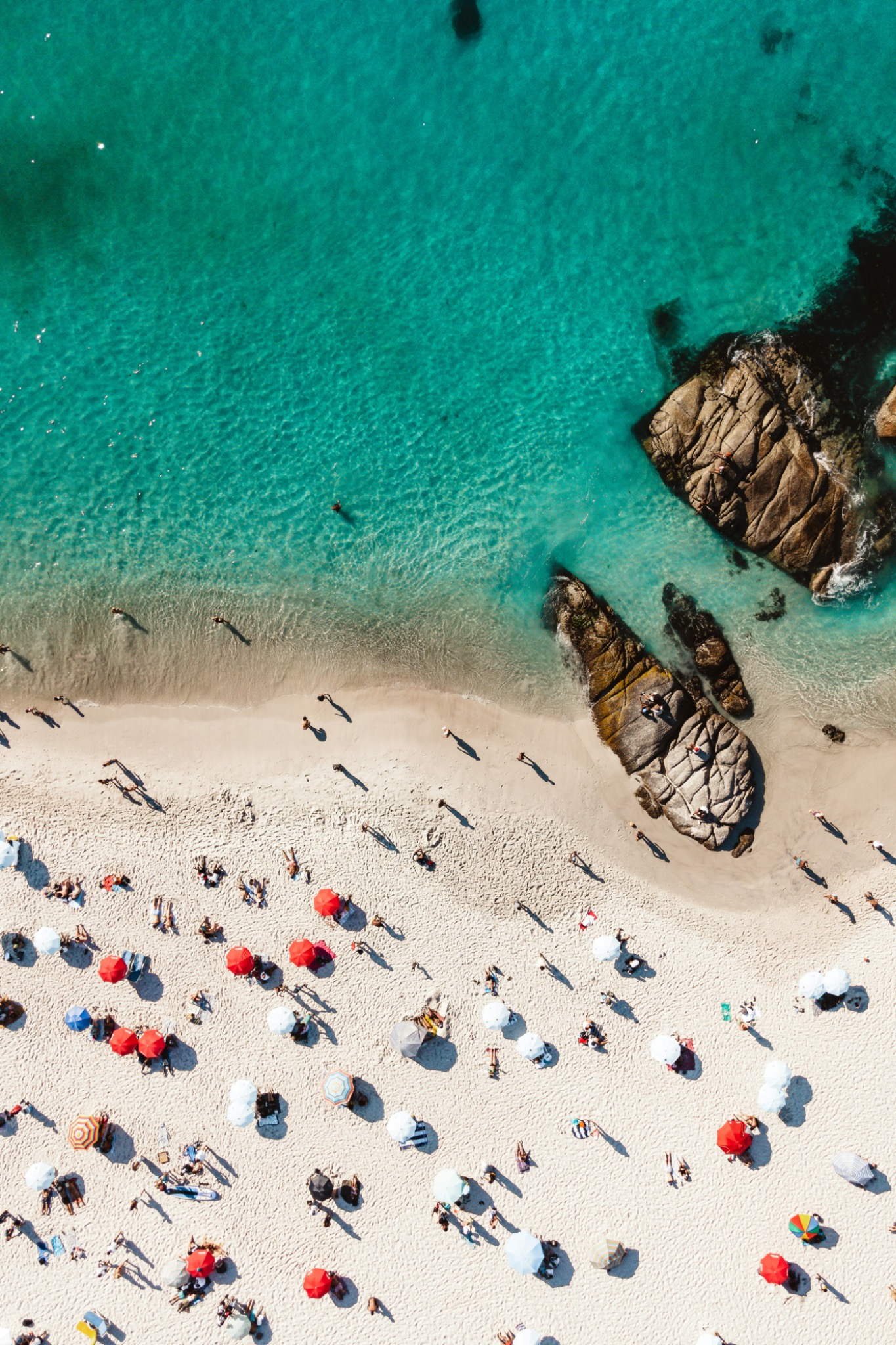 Vista cenital de una playa con sombrillas y agua turquesa